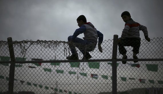 Palestinian boys sit on a fence as they watch a Hamas rally in Khan Younis in the southern Gaza Strip