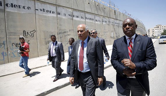 Head of the Palestinian Football Association Rajoub walks with anti-apartheid activist Sexwale past Israel’s controversial barrier as they arrive for a news conference in the West Bank town of Al-Ram