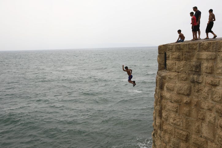 A young boy jumps off a tall wall in Akko