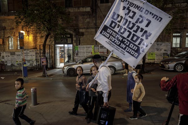 An Orthodox Jew walks through the streets of Mea Shearim, the ultra-Orthodox neighbourhood of Jerusalem, with a sign that reads "Life is happy only without the internet and movies" 