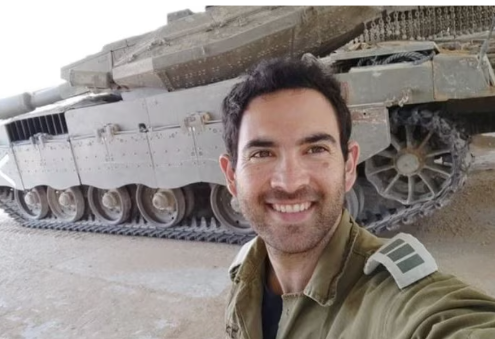 Man in army uniform in front of a tank