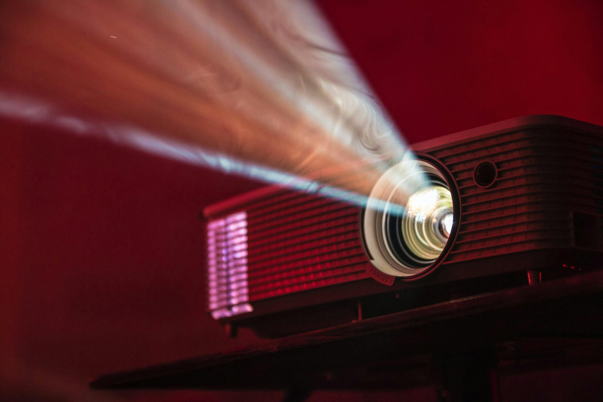 Film projector streaming light on a red background