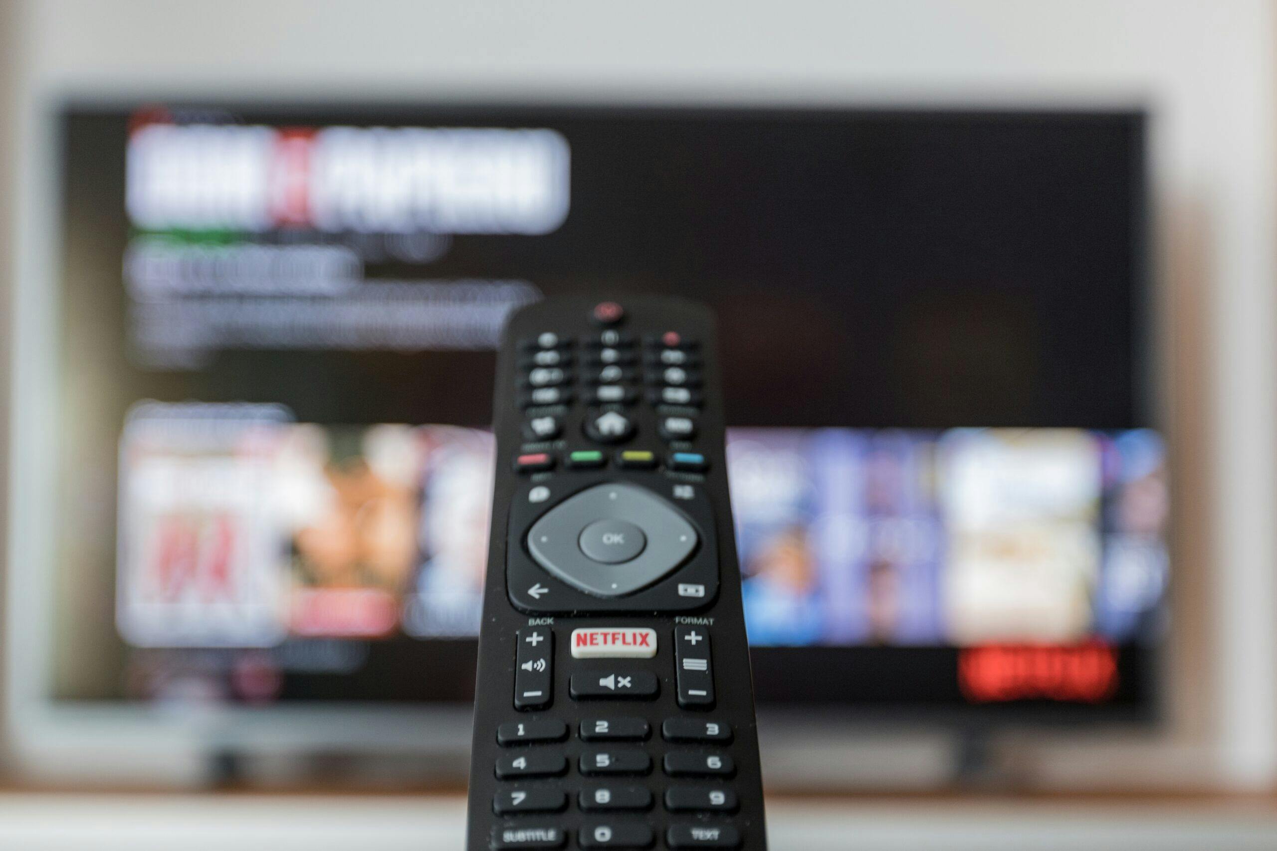 A remote pointing to a TV that is showing Netflix