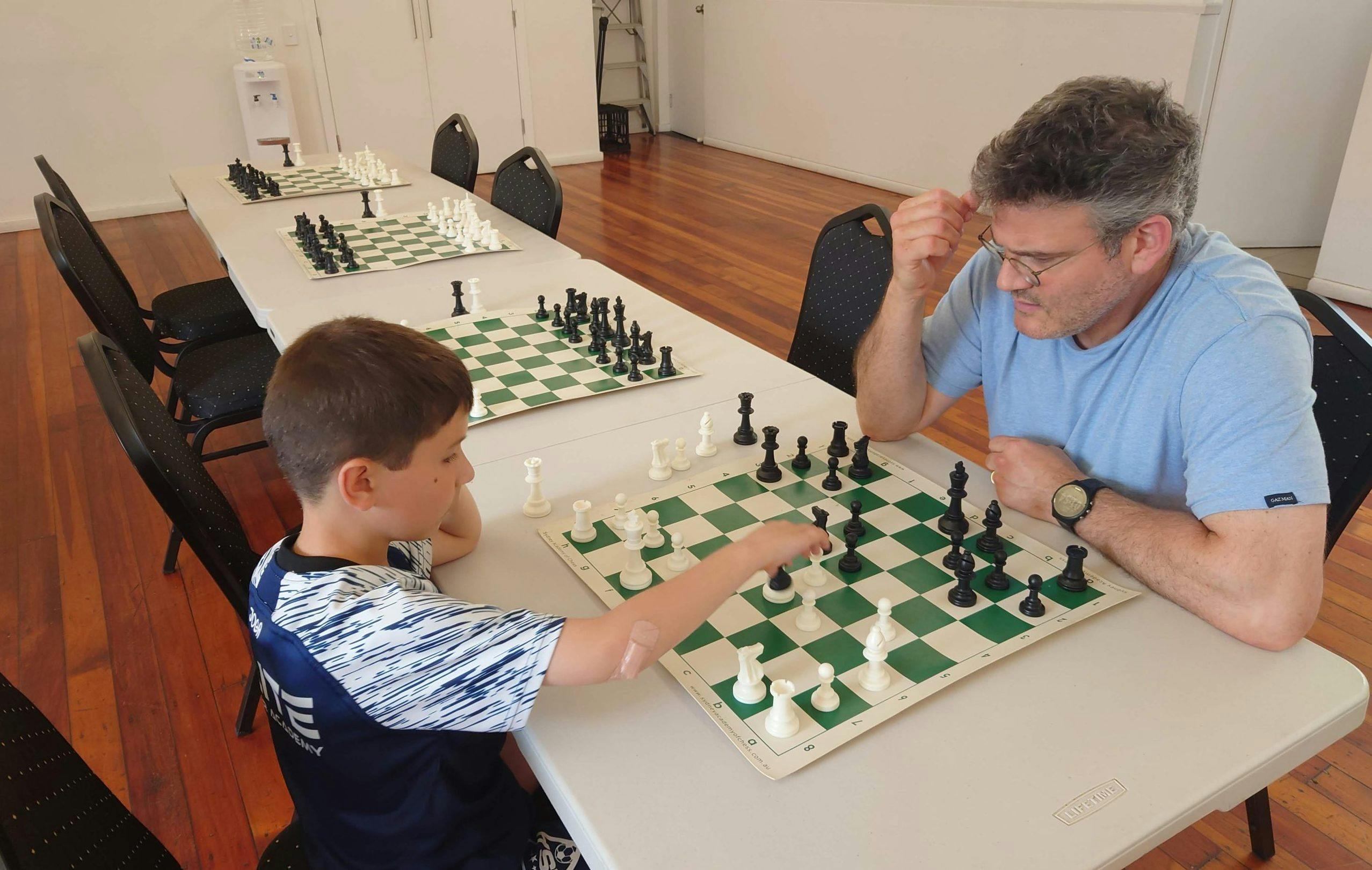 A young boy versing an older man at chess.